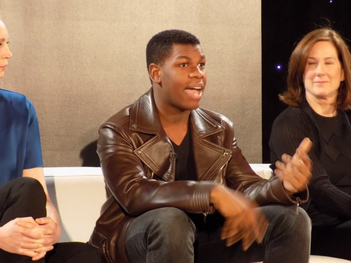 John Boyega at the Star Wars: The Force Awakens press event answering questions from Mindy Kaling and the press